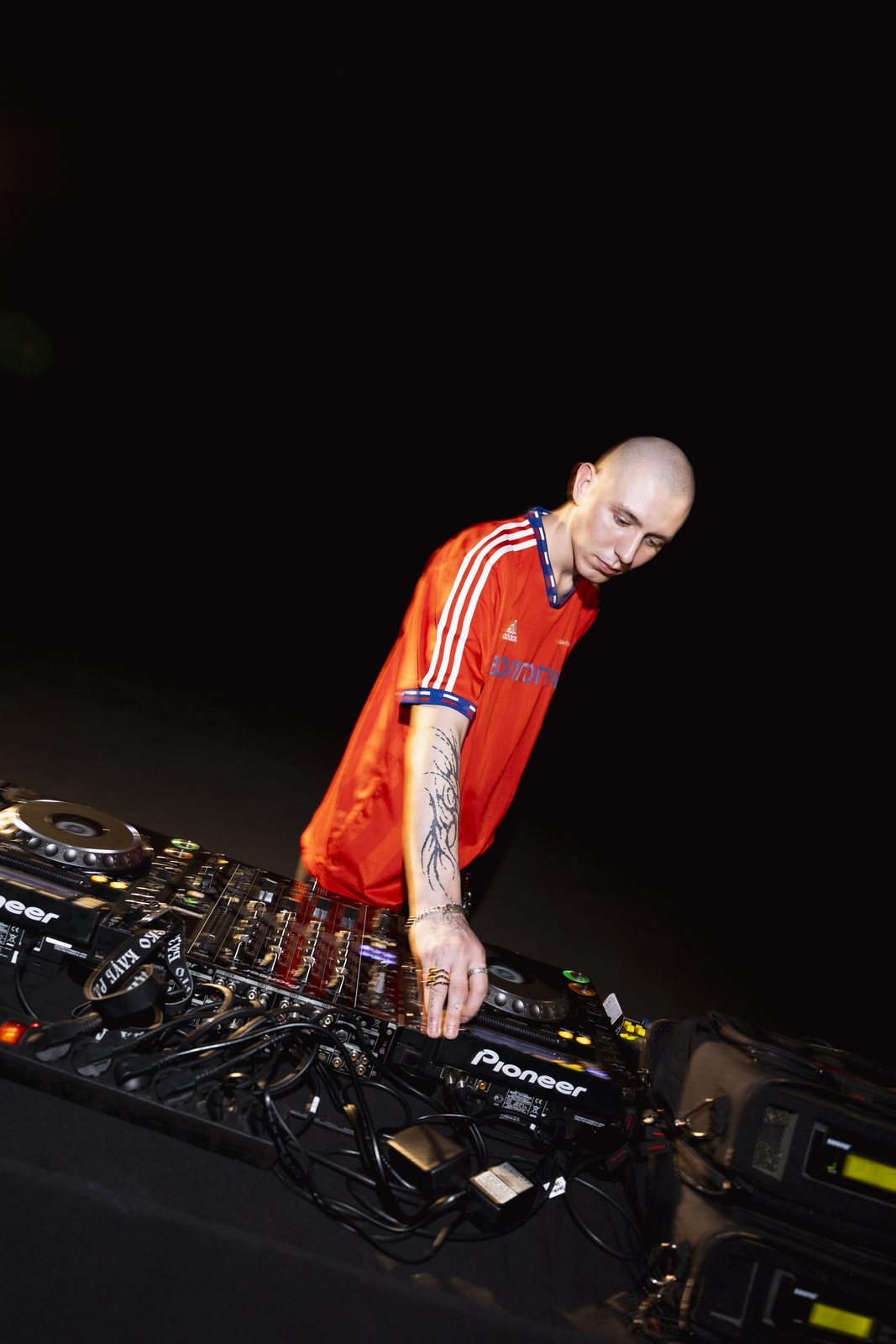 NOKIANGEL performing at a DJ setup in a red shirt