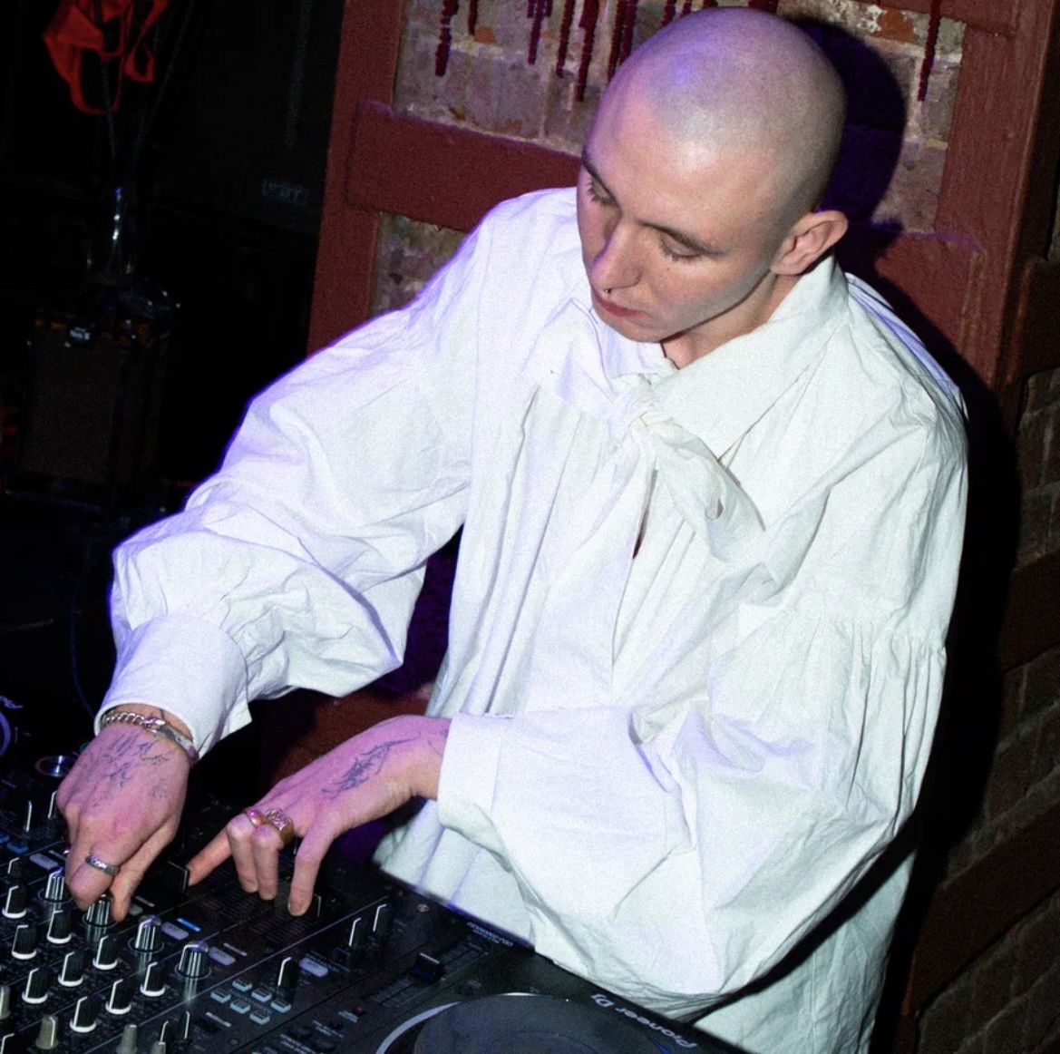 NOKIANGEL performing behind the decks in a white shirt